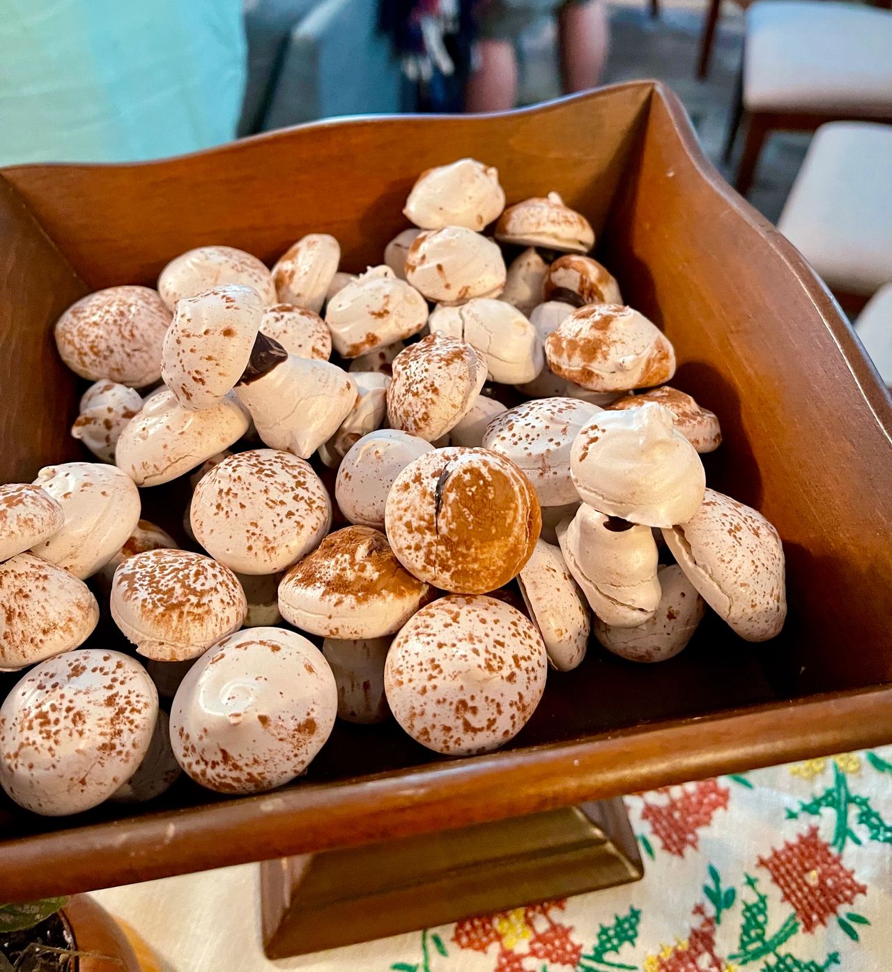 Meringue mushrooms displayed in a vintage wooden stand.
