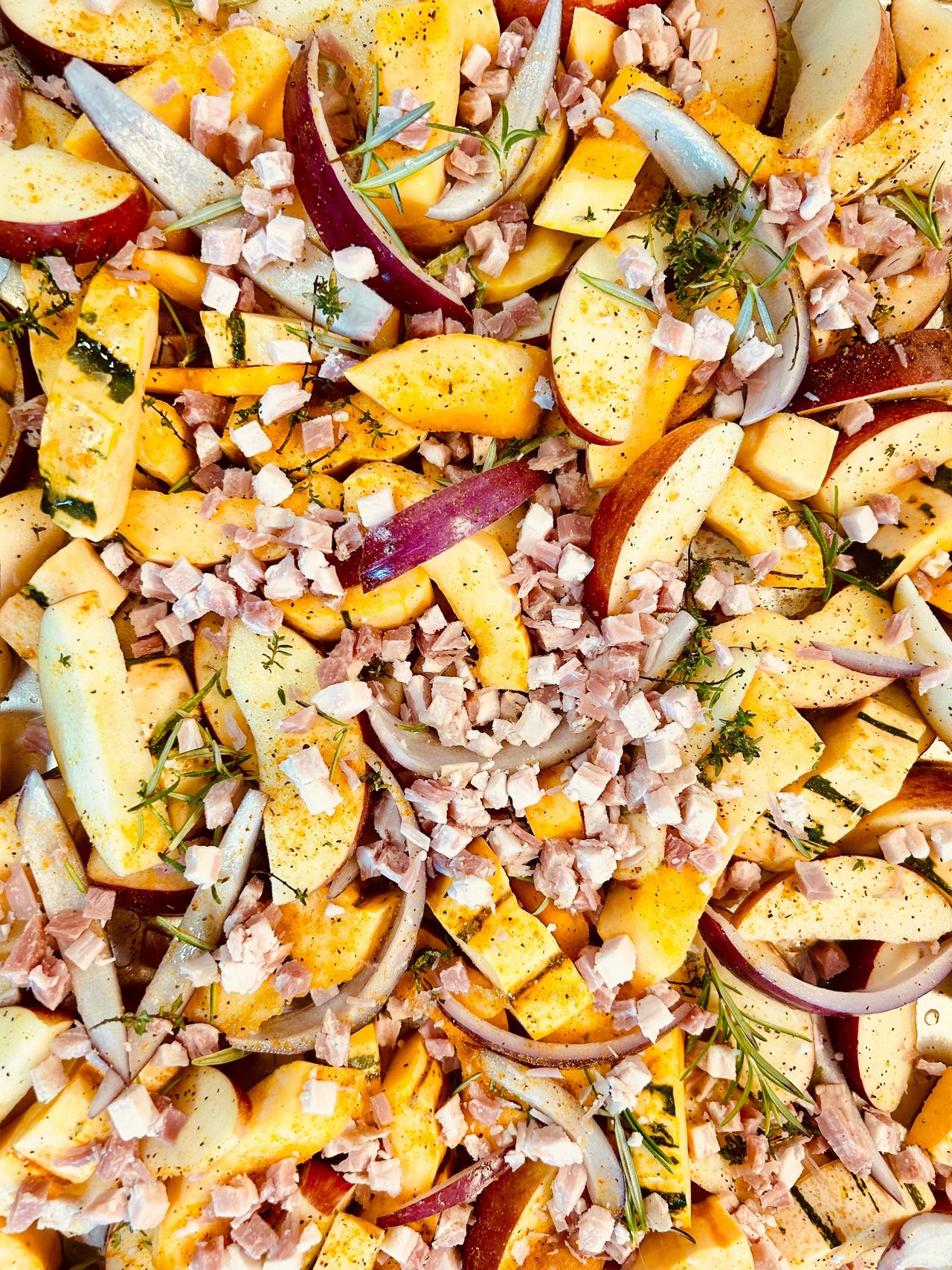 Squash, apples, onions and pancetta on a roasting pan.