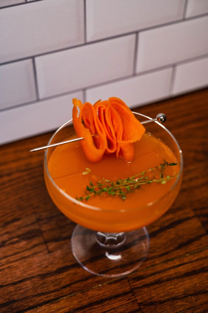 Carrot and thyme garnish on carrot bourbon cocktail