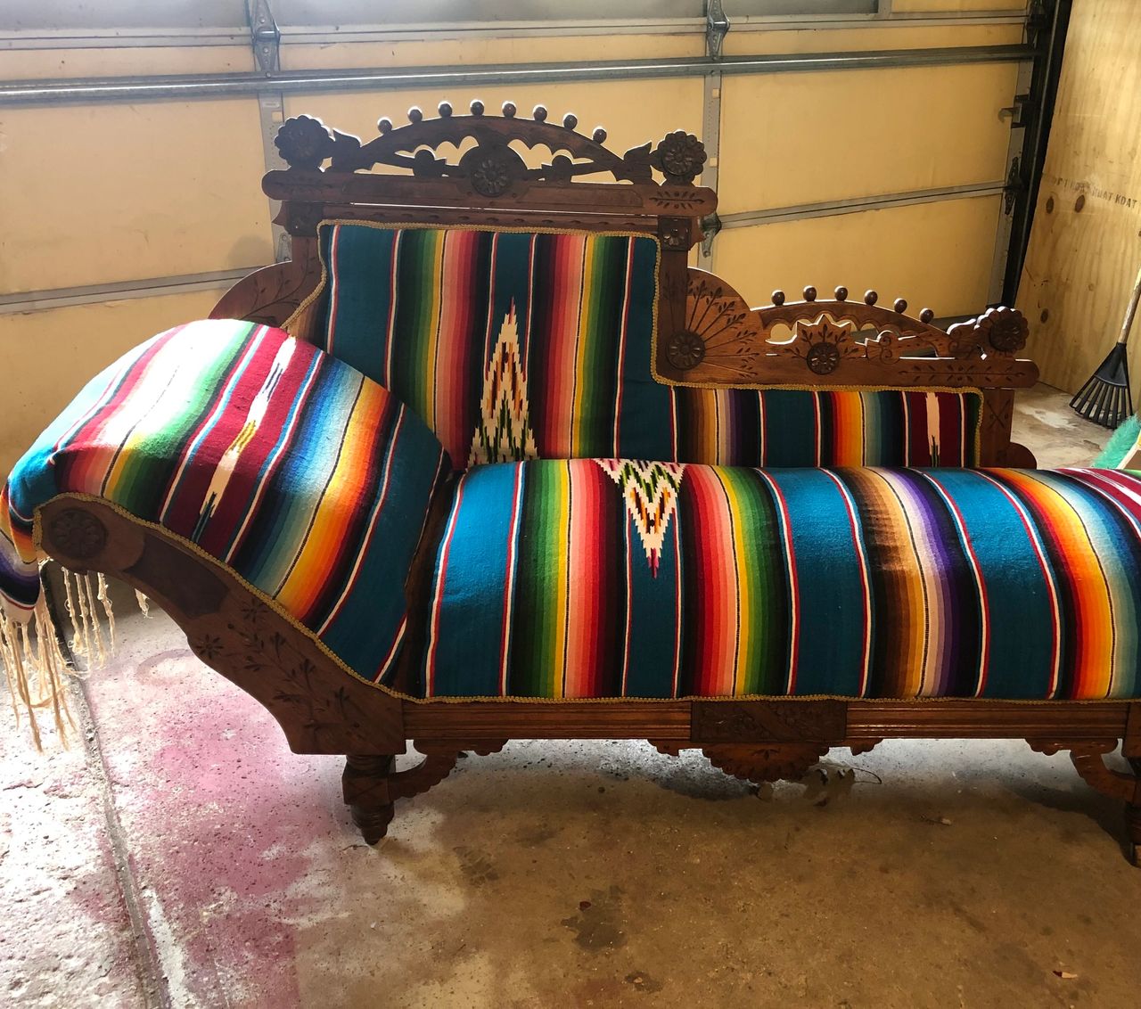 Vintage chaise lounge covered in Mexican blanket in a garage