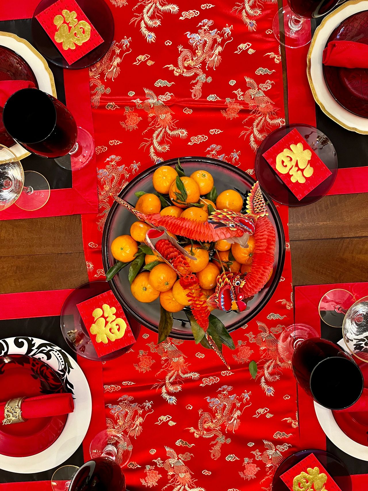 Tangerines and dragons on a red table runner.