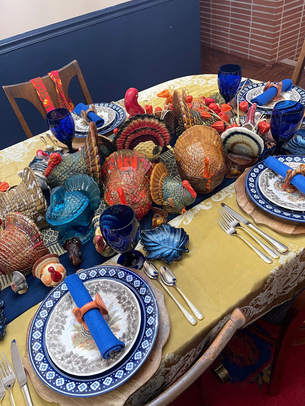 Blue, gold and brown dishes and ceramic turkeys on a table.