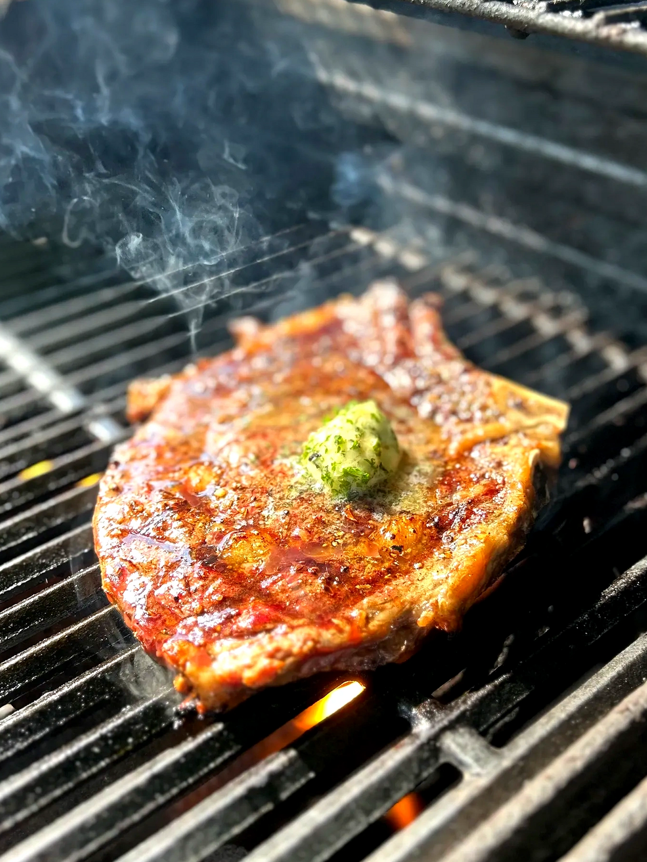 Steak cooked on a grill, smoke in the background